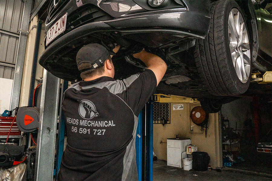 Meads Mechanic working on vehicle whilst on car hoist